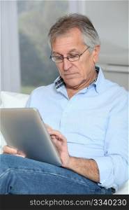Senior man sitting in sofa with electronic tablet