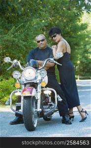 Senior man sitting on a motorcycle with a mature woman standing beside him