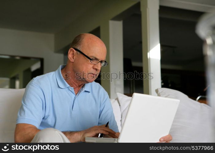 Senior man sitting on a sofa in front of a laptop computer