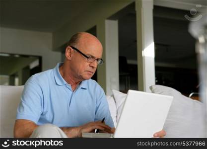 Senior man sitting on a sofa in front of a laptop computer
