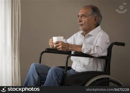 Senior man sitting on a wheelchair with a coffee cup. (Health and fitness) 