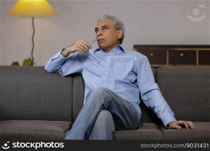 Senior man sitting on sofa and looking away 