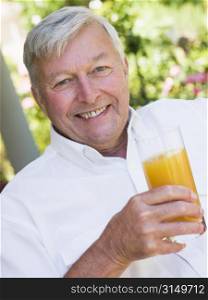Senior man sitting outdoors with a glass of orange juice