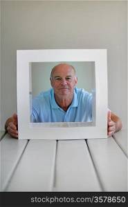 Senior man sitting with a white frame