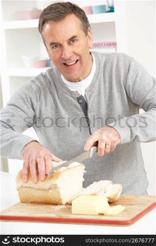 Senior Man Slicing Bread In Kitchen