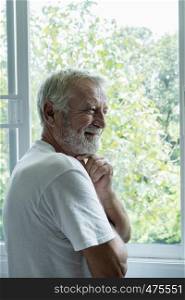 senior man smiling and thinking with happiness in white room