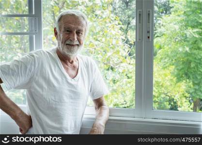 senior man smiling and thinking with happiness in white room