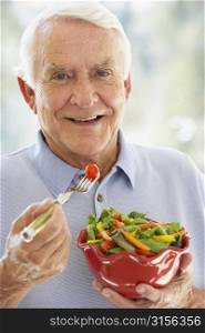 Senior Man Smiling At Camera And Eating Salad