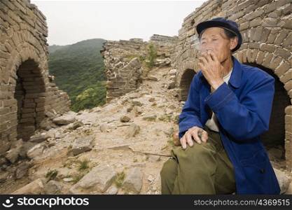 Senior man smoking on a wall, Great Wall Of China, Beijing, China