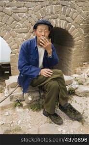 Senior man smoking on a wall, Great Wall Of China, Beijing, China