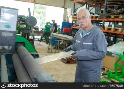senior man ssing metal through rollers