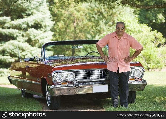 Senior man standing in front of a convertible car in a park