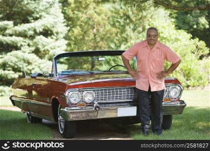 Senior man standing in front of a convertible car in a park