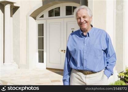 Senior man standing outside his home