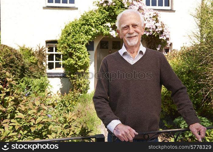 Senior Man Standing Outside Pretty Cottage