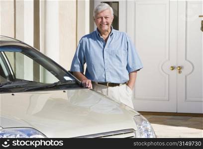 Senior man standing with his car outside his home