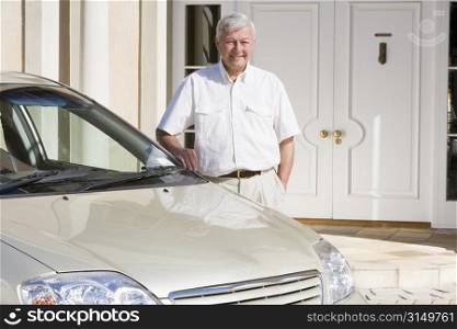 Senior man standing with his car outside his home