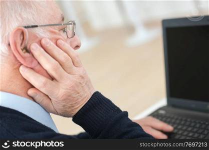 senior man suffering from deafness with computer