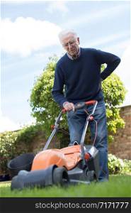 Senior Man Suffering With Backache Whilst Using Electric Lawn Mower To Cut Grass At Home
