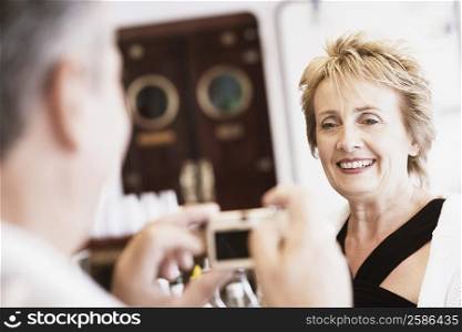 Senior man taking a picture of a mature woman with a digital camera and smiling
