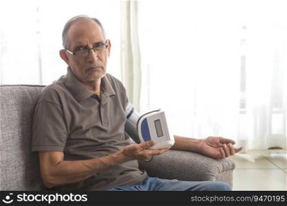 Senior man taking his blood pressure test at home. (Health and fitness) 