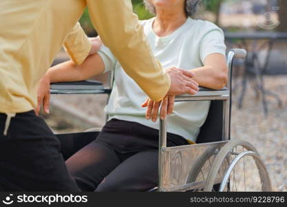 Senior man talking and take care disabled wife in wheelchair while relaxing with happiness in park.