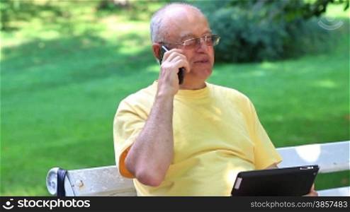 Senior man talking on smart phone in summer park