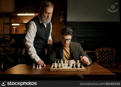 Senior man teaching young guy playing chess explaining rules of game. Educational leisure. Senior man teaching young guy playing chess explaining rules of game