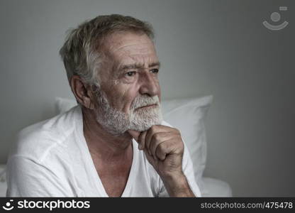 senior man thinking or try to remember alone on bed in white room