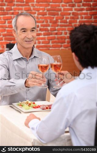 senior man toasting with someone younger
