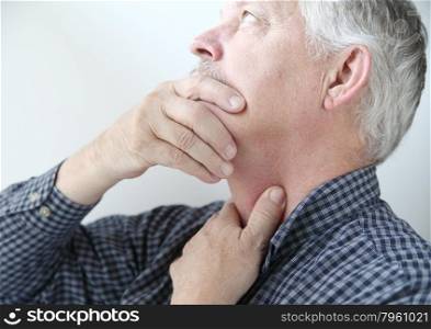 senior man touches area on neck where he feels pain
