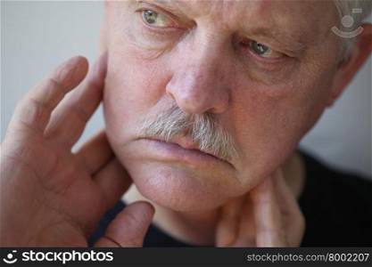 Senior man touches his sore jaw area.