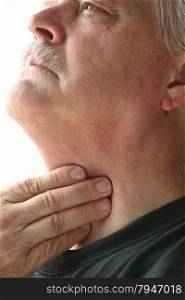Senior man touches the area of his throat pain.