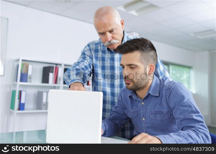 Senior man training man on computer