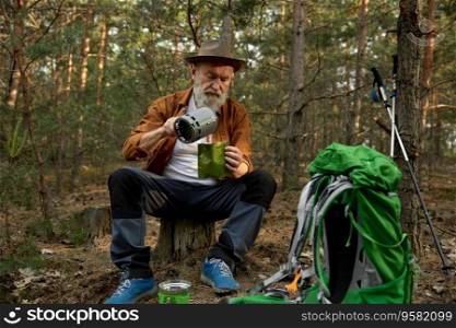 Senior man traveler cooking dinner in the forest. Grandfather enjoying hiking leisure activity on nature. Senior man traveler using portable gas burner to cook dinner