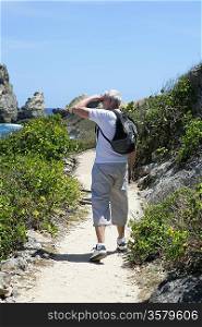 Senior man using binoculars by the coast