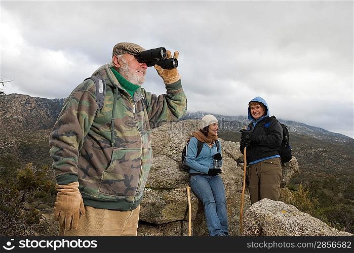 Senior man using binoculars in mountains