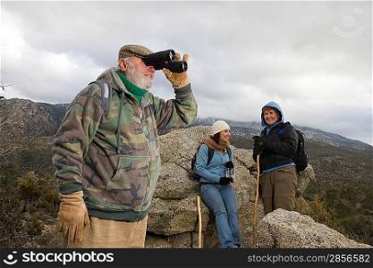 Senior man using binoculars in mountains