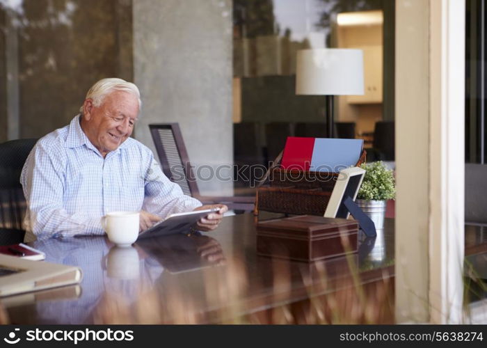 Senior Man Using Digital Tablet Through Window