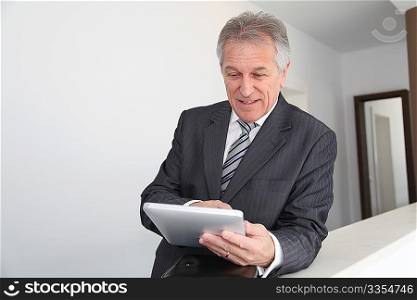 Senior man using electronic tab in building hall