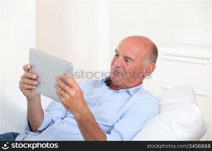 Senior man using electronic tablet at home