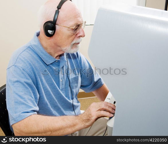 Senior man using headphones and voting on one of the newest touch screen machines (in florida and other states).