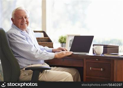 Senior Man Using Laptop On Desk At Home