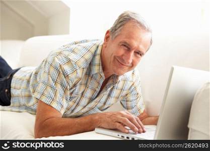 Senior Man Using Laptop Relaxing Sitting On Sofa At Home