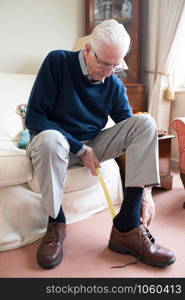 Senior Man Using Long Handled Shoe Horn To Put On Shoes