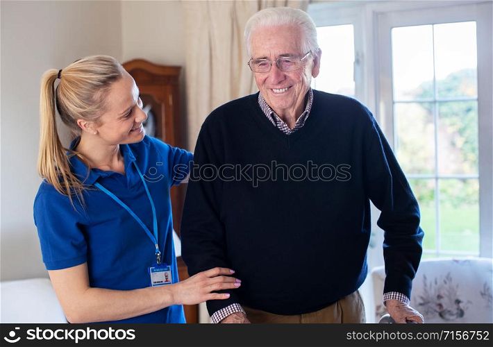 Senior Man Using Walking Frame Being Helped By Care Worker