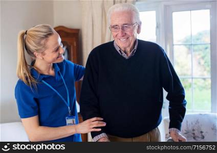 Senior Man Using Walking Frame Being Helped By Care Worker