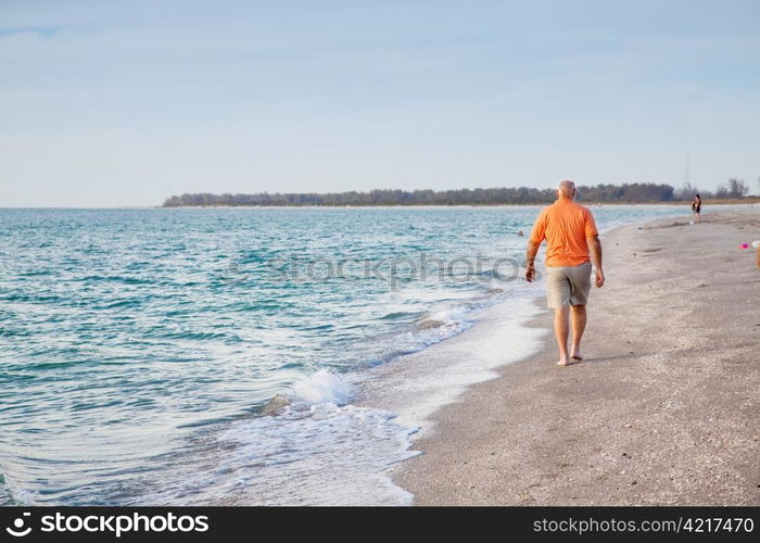 Senior man walking on the beach alone.