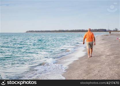 Senior man walking on the beach alone.