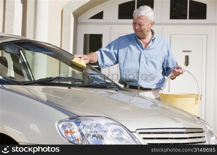Senior man washing his car outside house
